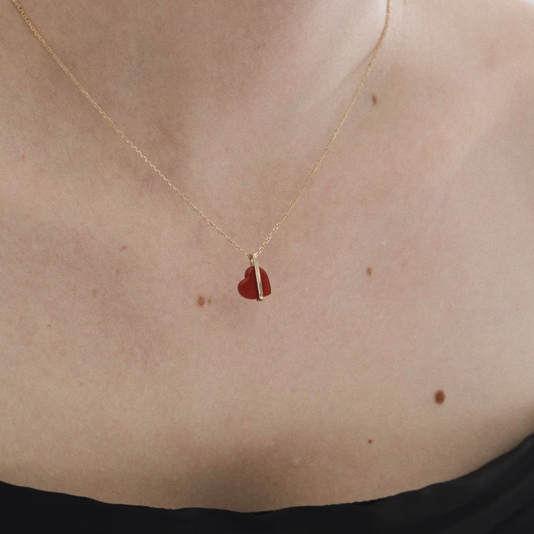 14K gold necklace with a red heart pendant on a person's neck