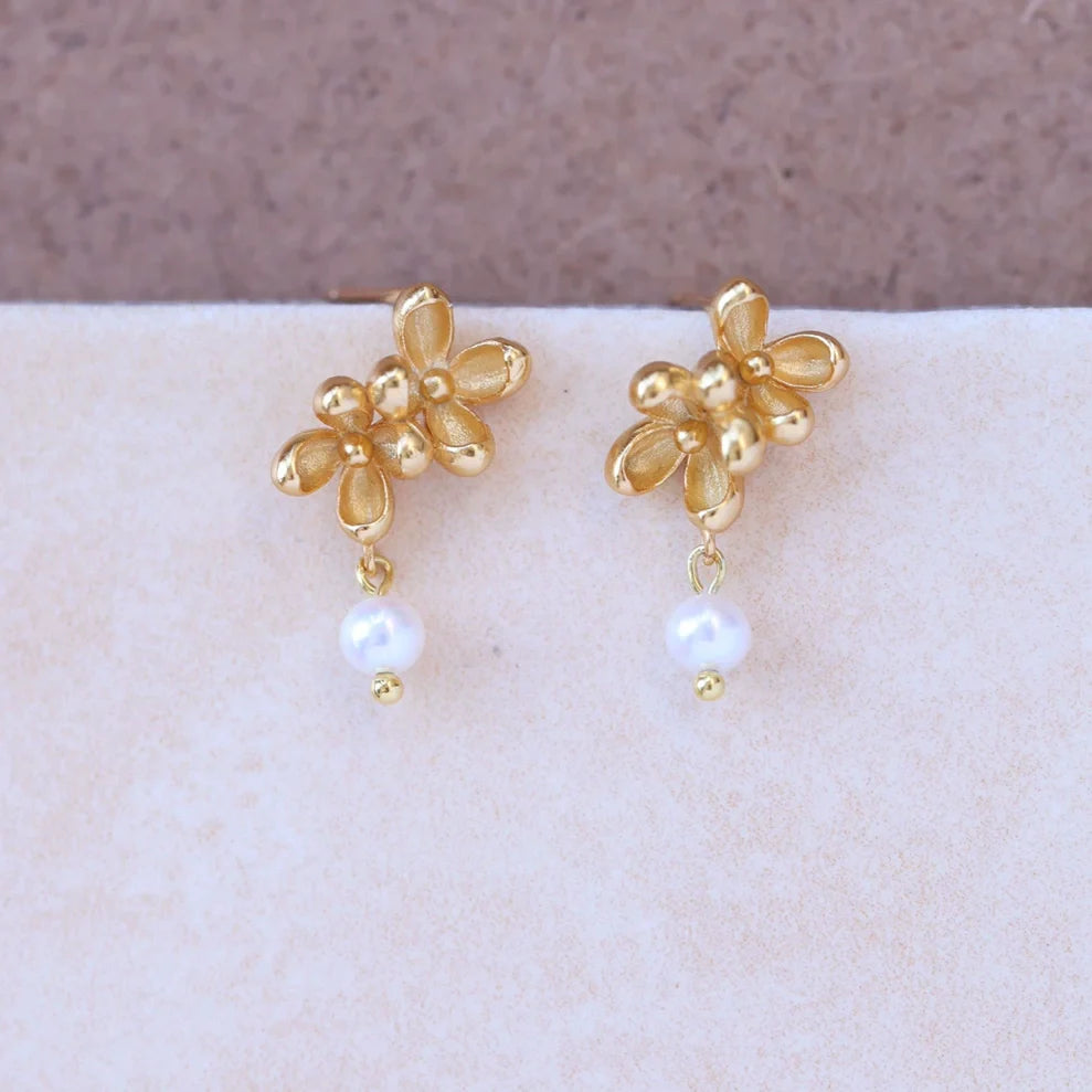 Close-up shot showing the matte texture of 18k gold flower petals and the luster of a natural freshwater pearl -1