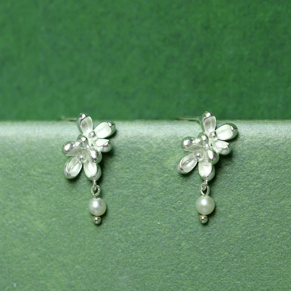 Close-up shot showing the matte texture of silver flower petals and the luster of a natural freshwater pearl -2