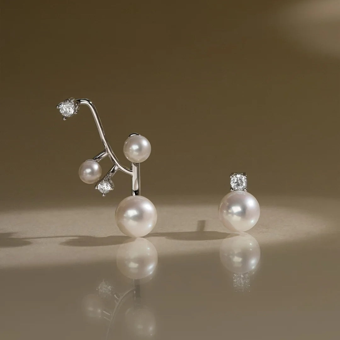 Pearl and diamond earrings on a reflective surface with a brown background