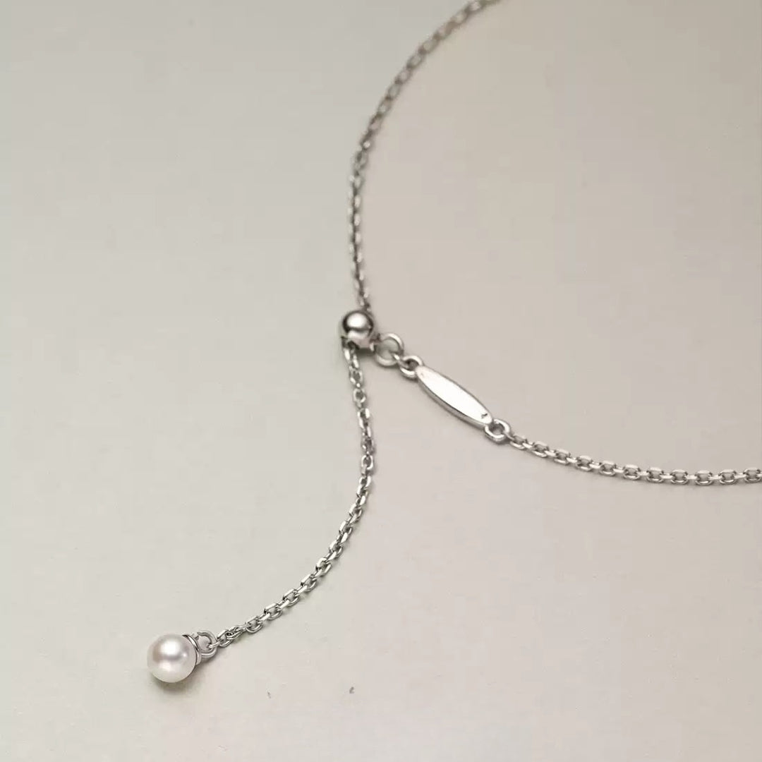 Silver necklace with a small pearl pendant on a light gray background