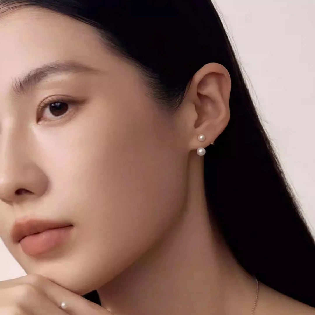 A high-angle portrait of a bride wearing a matching set of wrap-around pearl earrings and a geometric open ring, embodying a modern French minimalist style.
