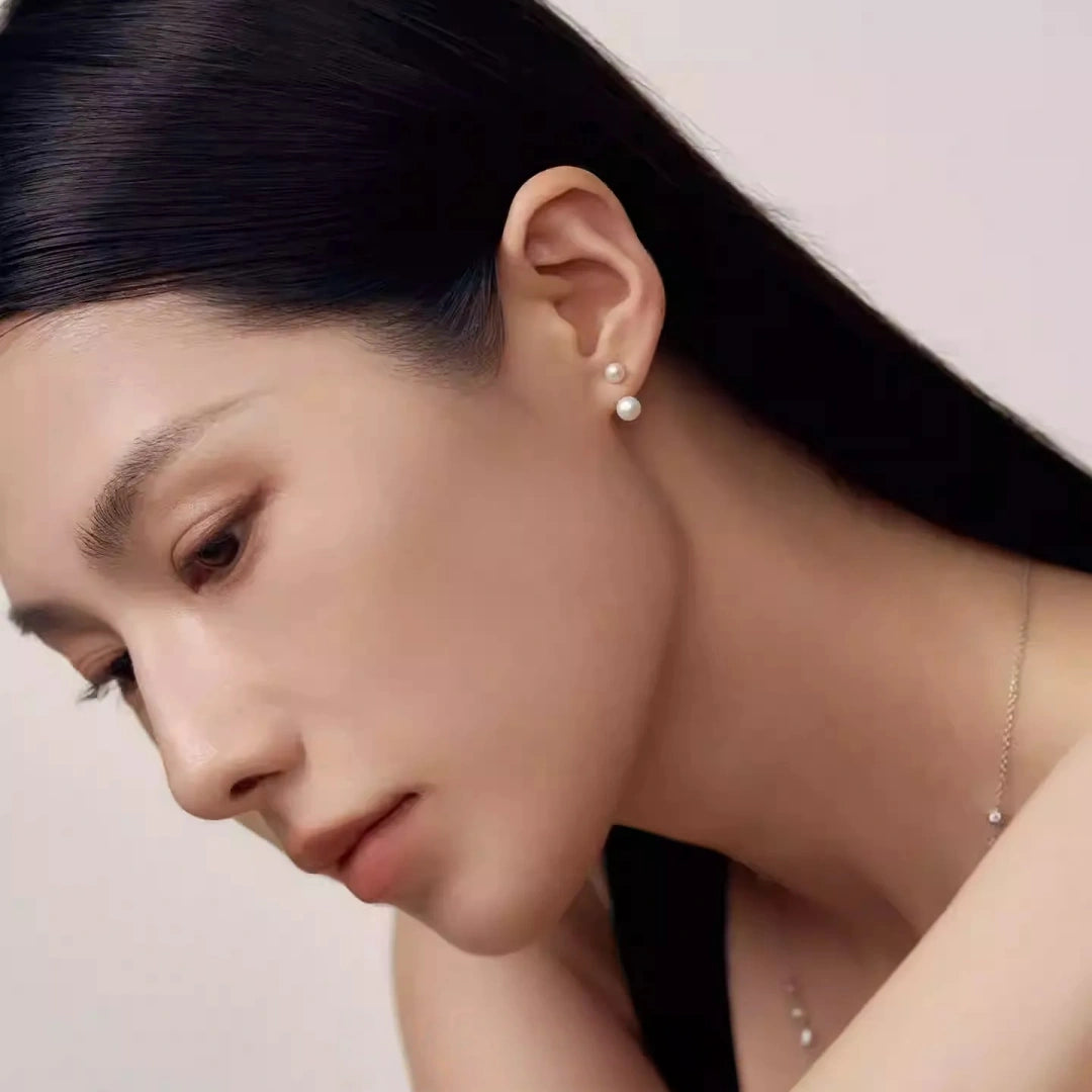 Detail shot of moving hands wearing a floating pearl open ring, showcasing the light-catching cubic zirconia and polished silver finish.