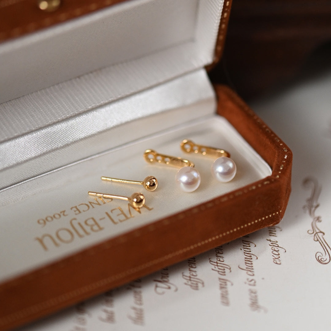 Gold and pearl earrings in a brown jewelry box.