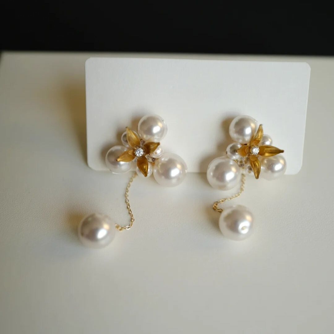 A pair of handcrafted vintage pearl flower earrings with a central gold flower surrounded by delicate pearls. The earrings feature a removable dangle, allowing them to be worn as pearl flower stud earrings or pearl cluster drop earrings. Perfect for brides, these dainty pearl flower earrings are ideal for floral wedding earrings or bridal flower earrings, offering versatile statement wedding bridal jewelry.