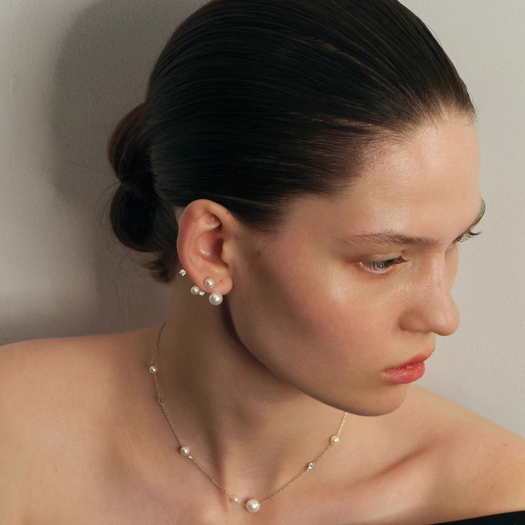 Woman wearing Celestial Pearl Diamond Earrings and earrings and pearl and diamond necklace against a neutral background