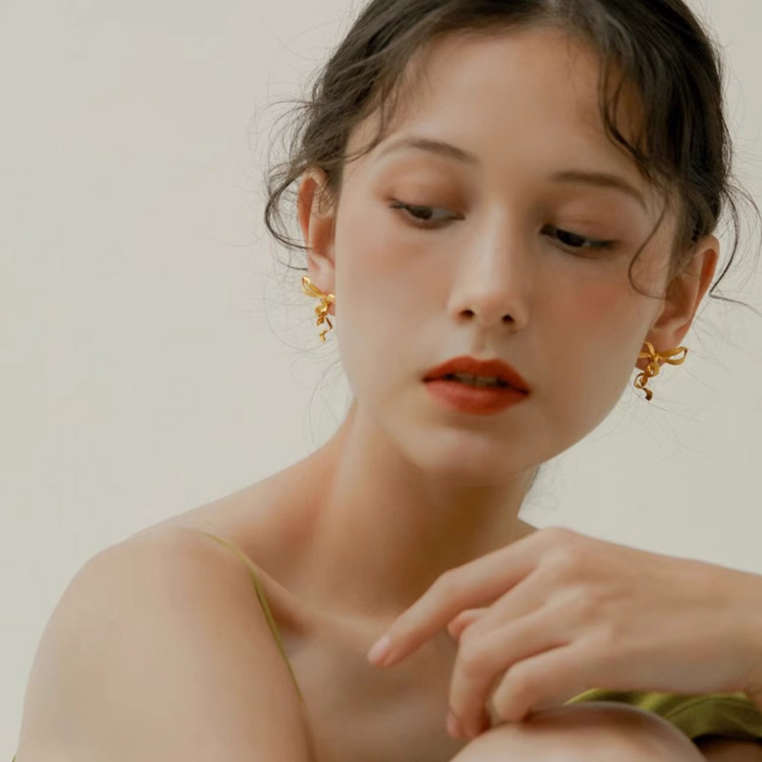 Front view of model wearing Sculptural Ribbon Bow gold earrings for elegant facial framing - model-look-2