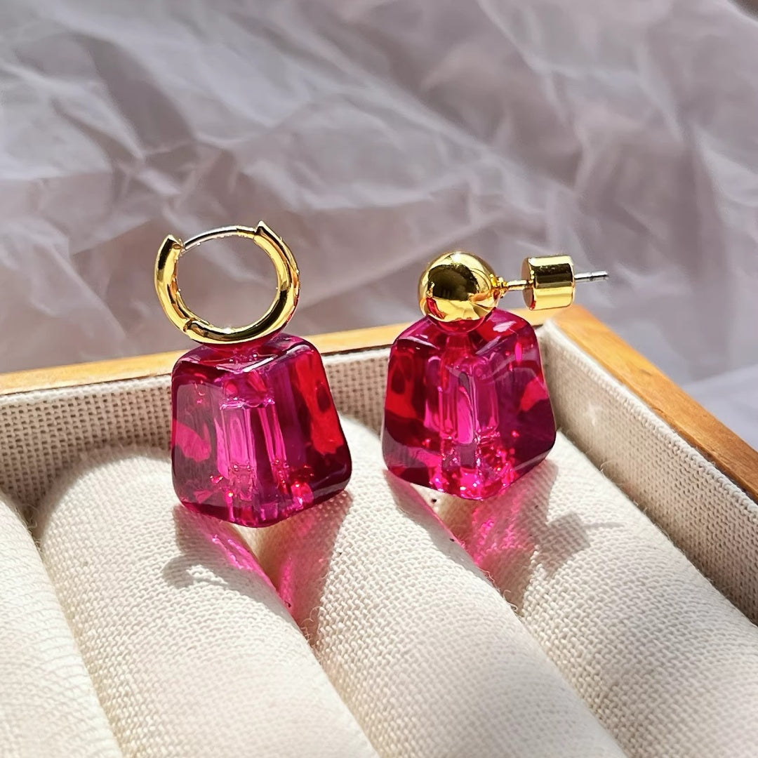 Magenta ice-cube earrings displayed in a luxury beige jewelry tray.